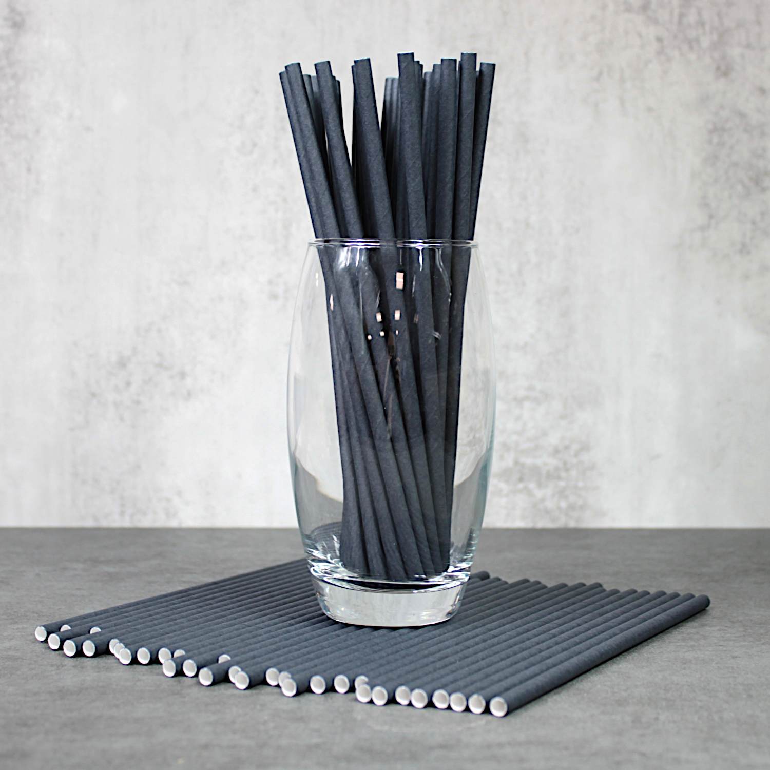 Our new stylish Midnight Black Paper Straws, positioned underneath a glass filled with other Midnight Black Paper Straws.